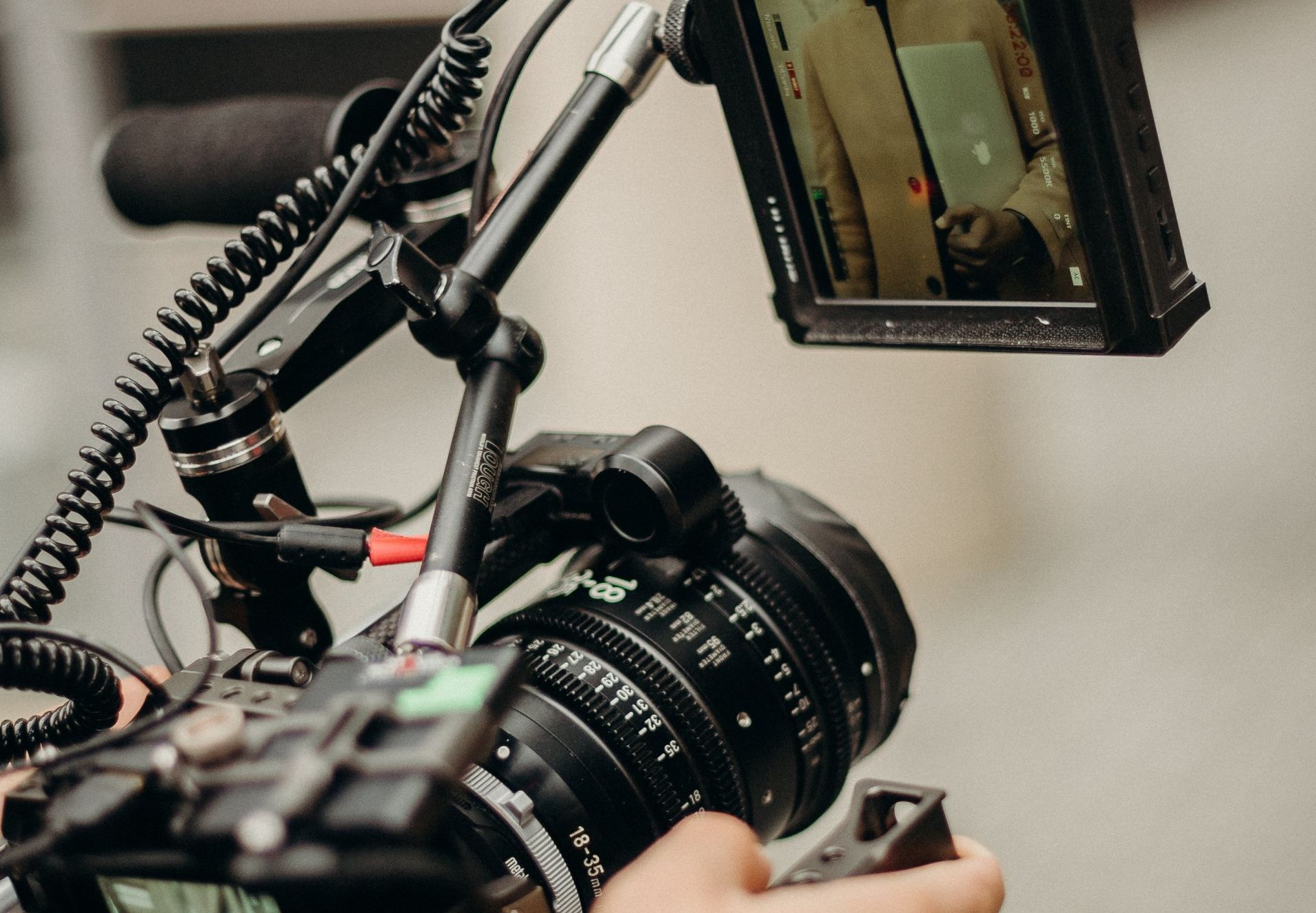 A person is holding a camera with a screen attached to it.