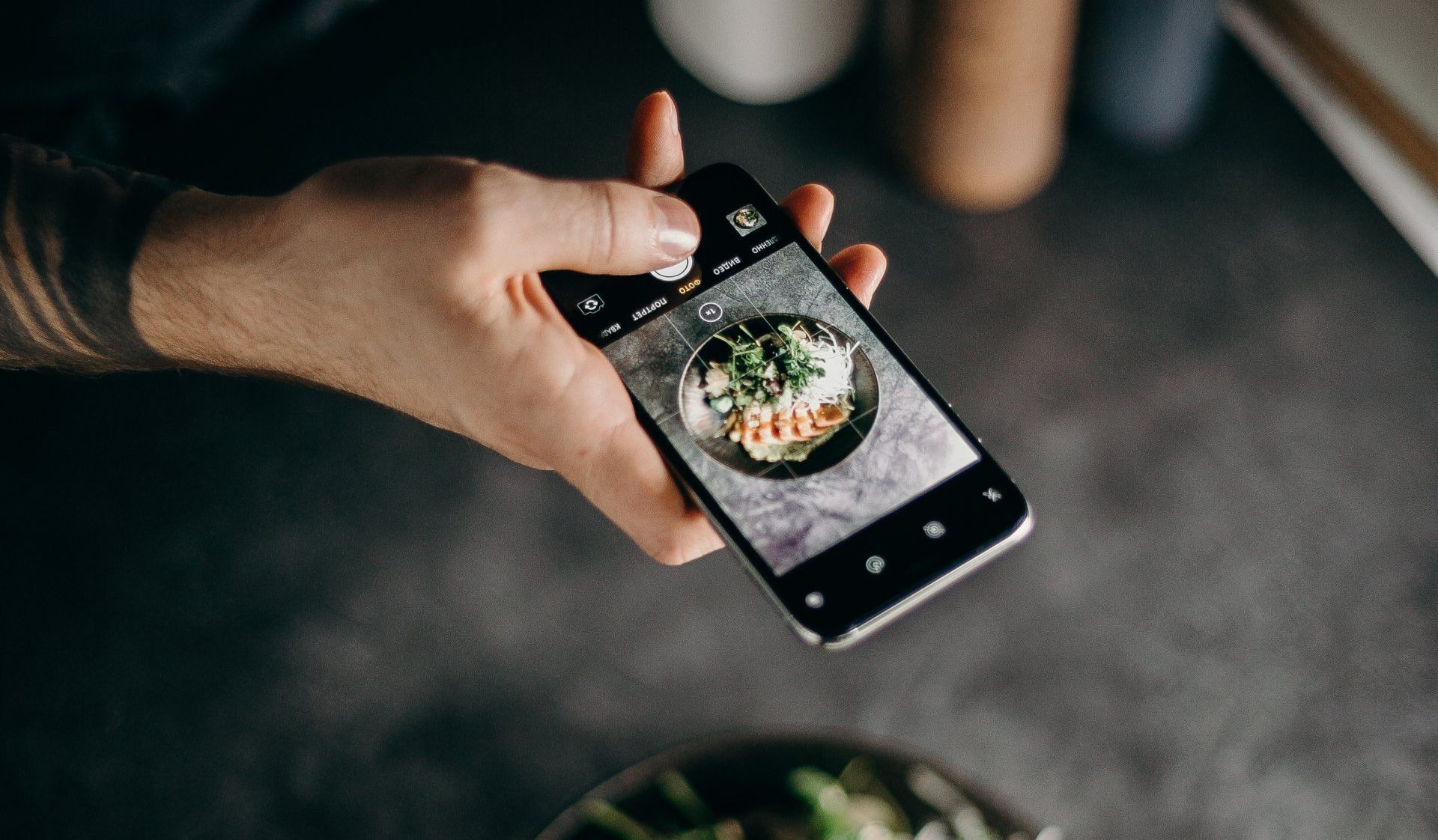 A person is taking a picture of a bowl of food on their cell phone.