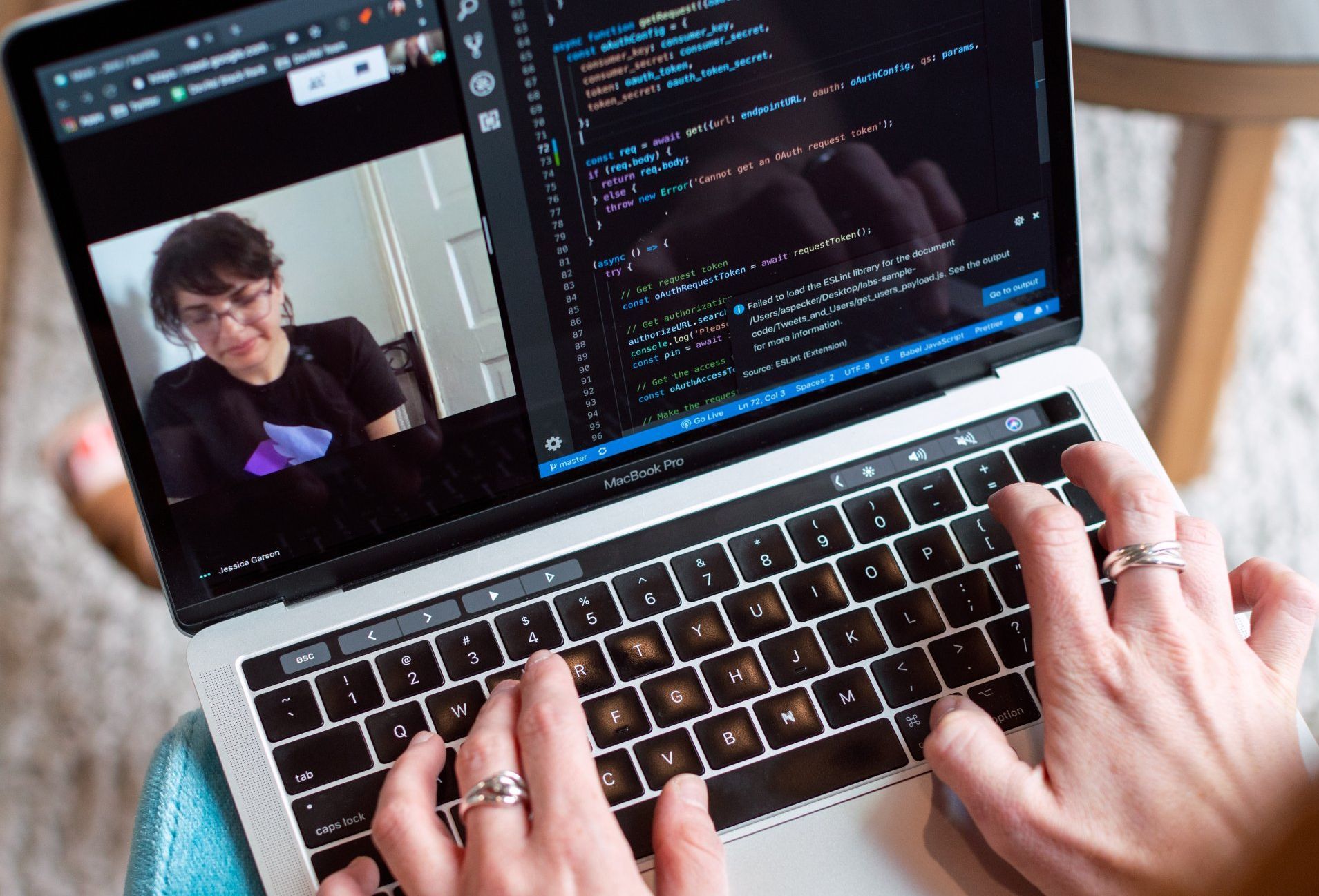 A person is typing on a laptop with a picture of a woman on the screen.