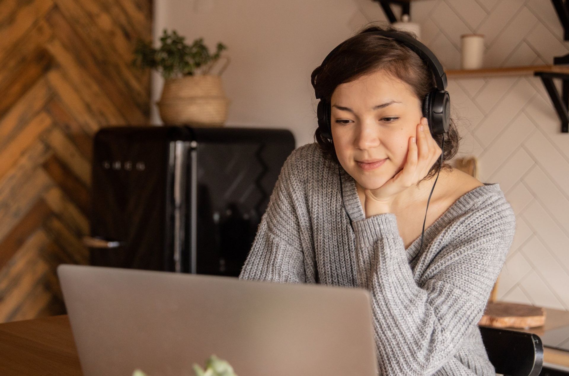 A woman wearing headphones is sitting in front of a laptop computer.