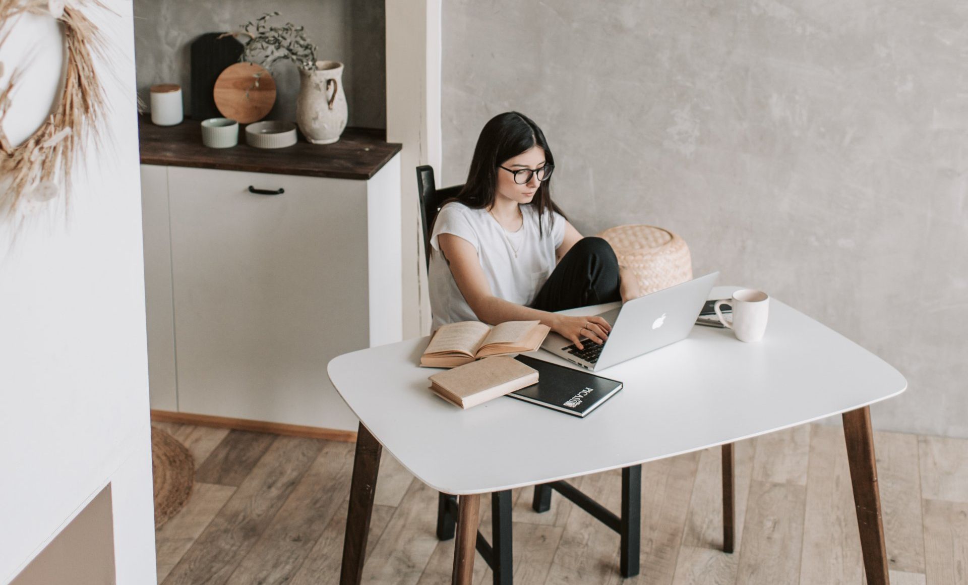 A woman is sitting at a table using a laptop computer.