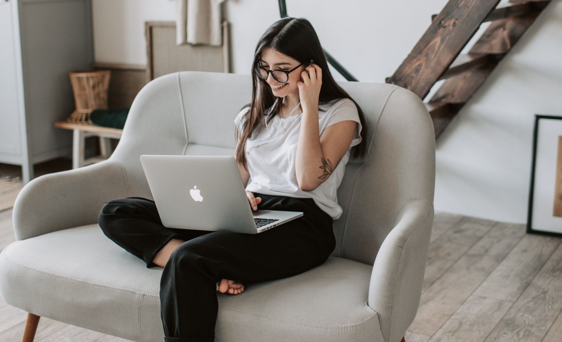 A woman is sitting in a chair using a laptop computer.