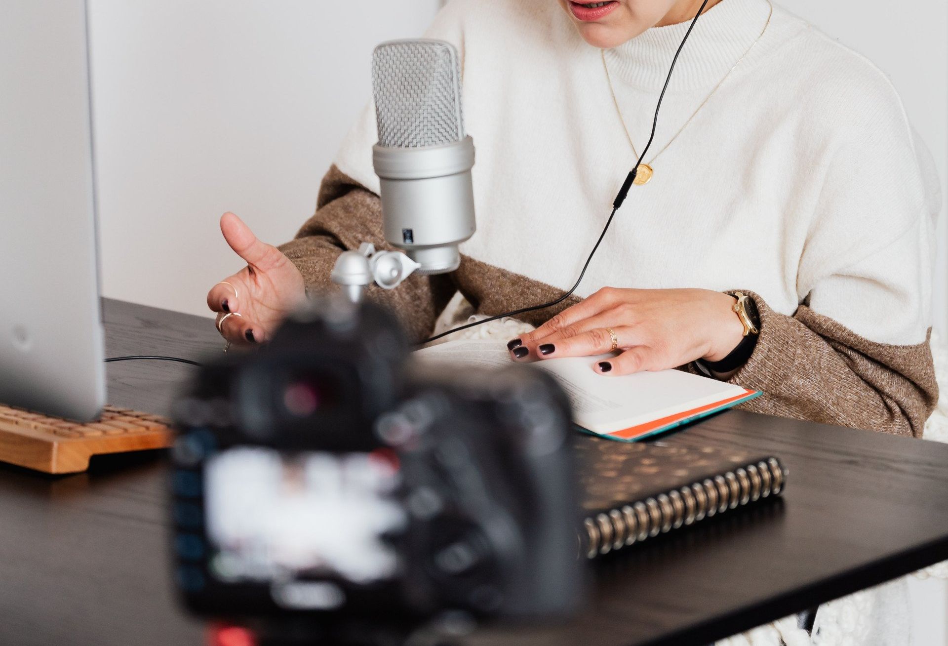 A woman is sitting at a desk talking into a microphone.
