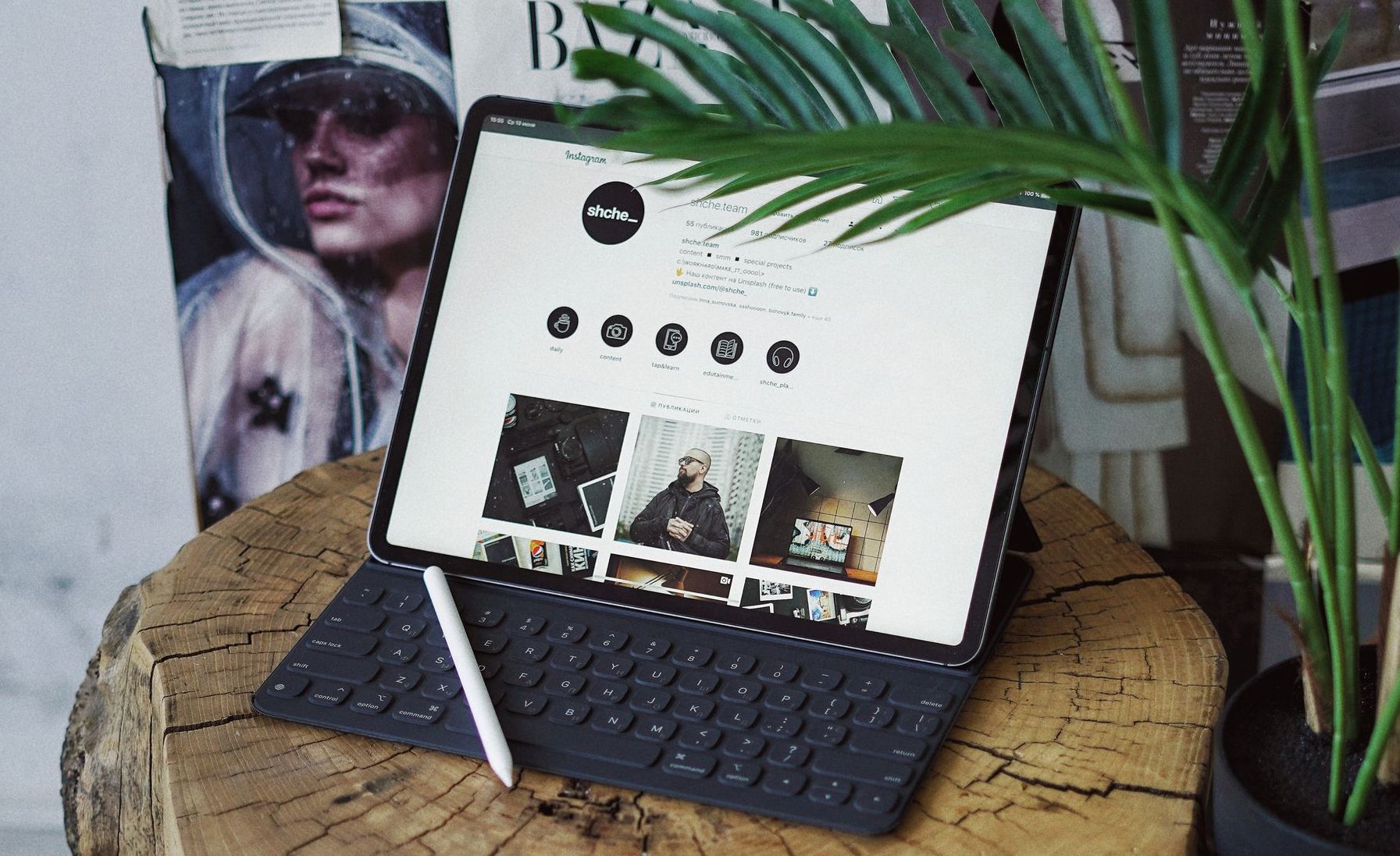 A tablet is sitting on top of a wooden stump next to a plant.