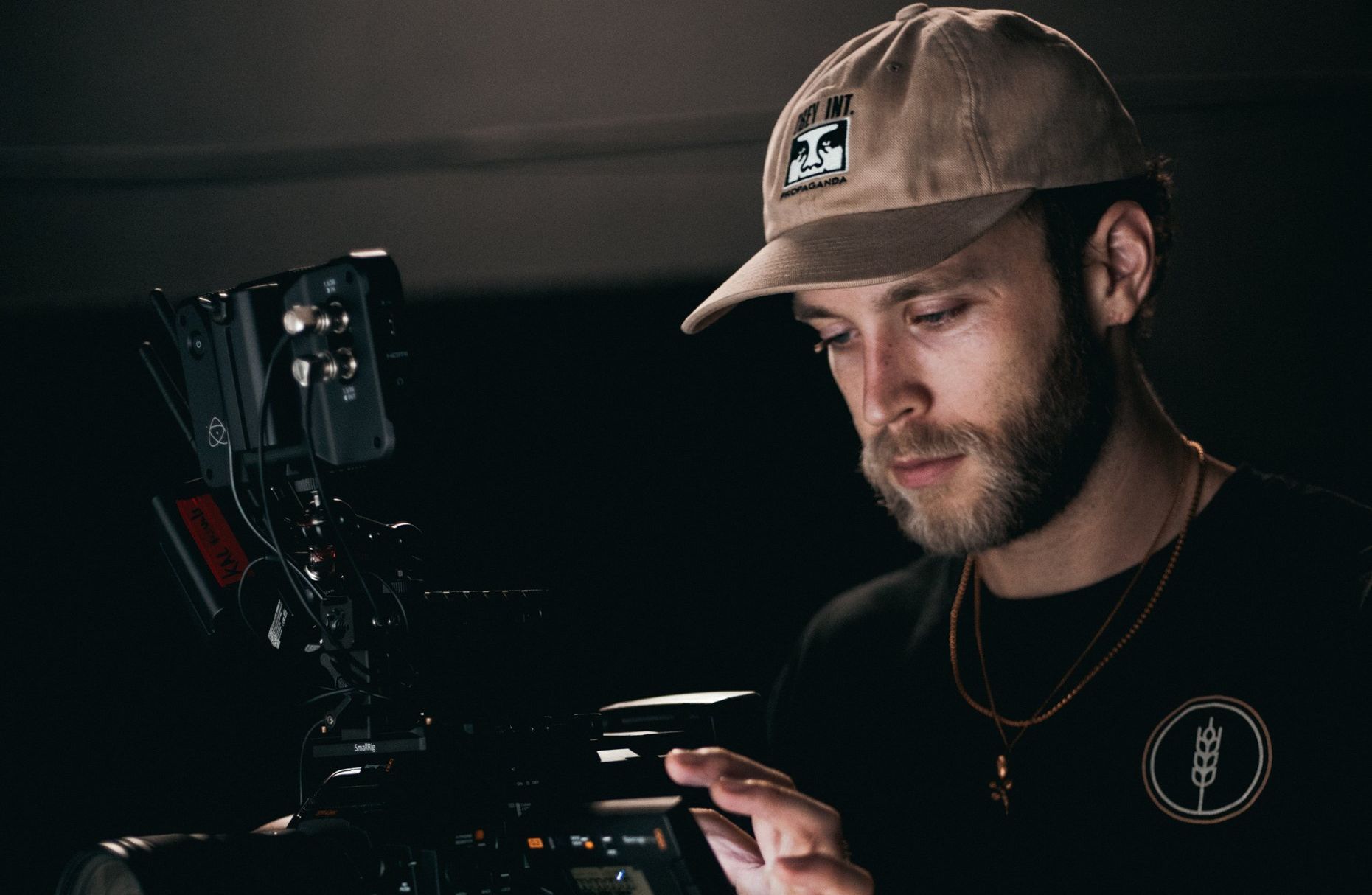 A man wearing a hat is looking at a camera.