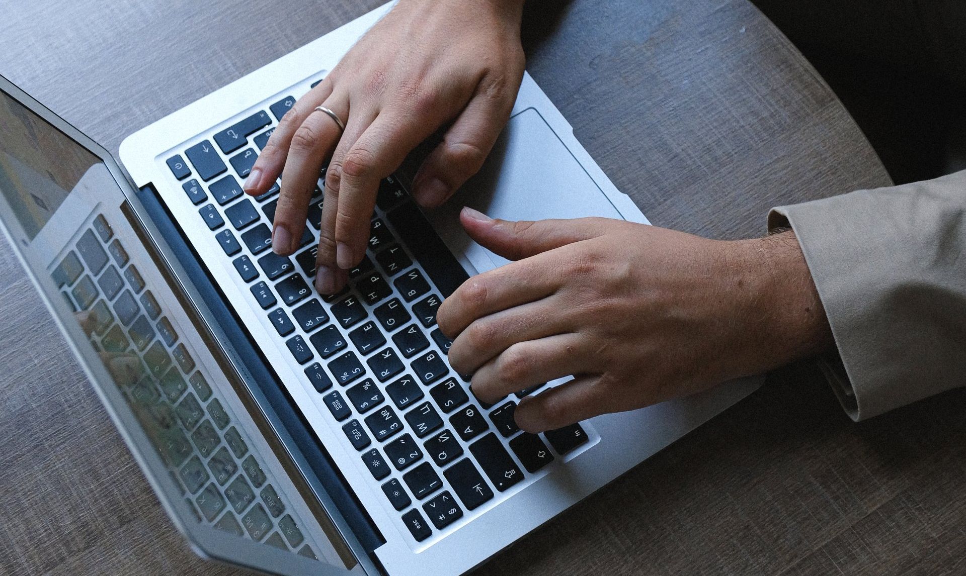 A person is typing on a laptop computer on a table.