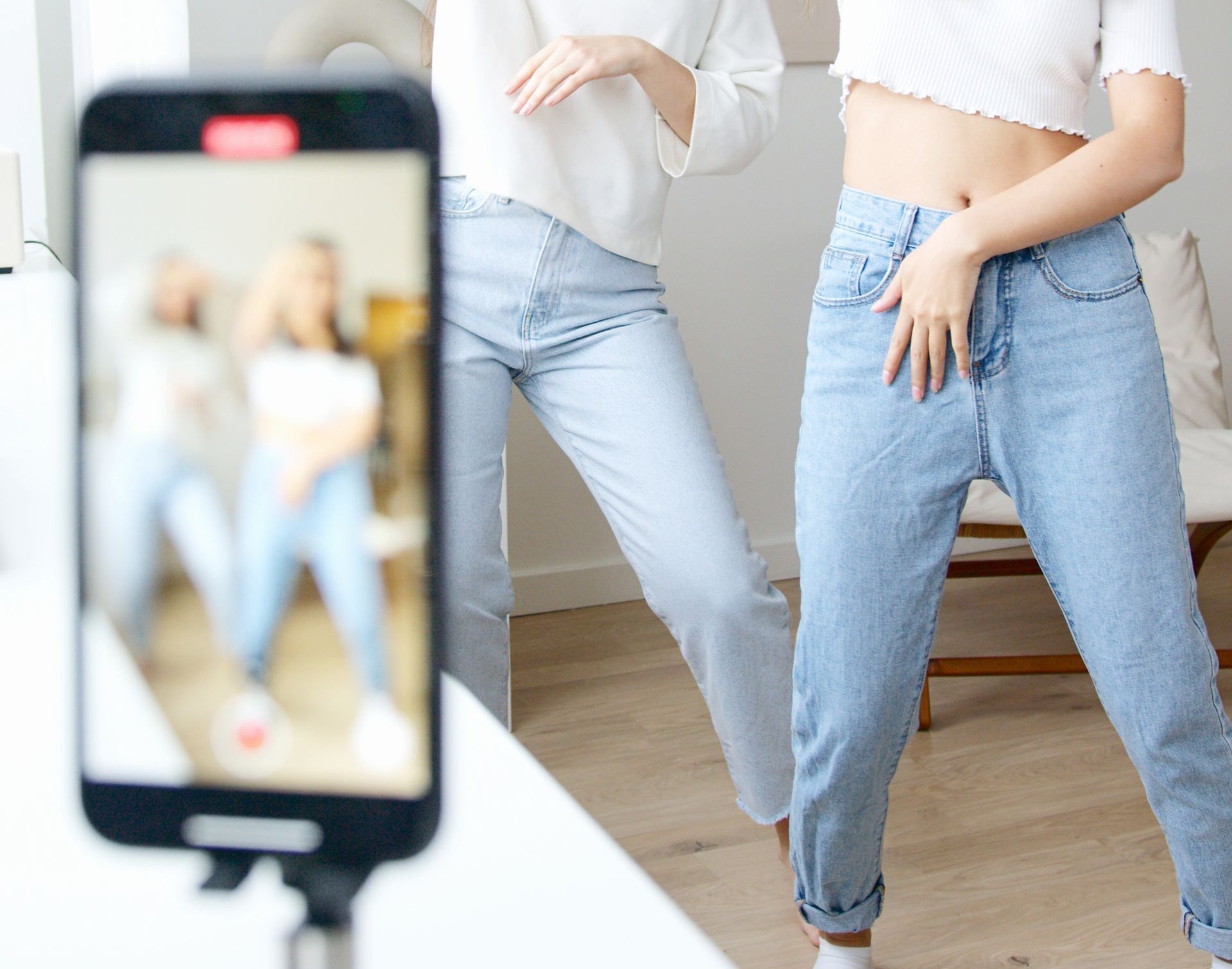 Two women are dancing in front of a cell phone.