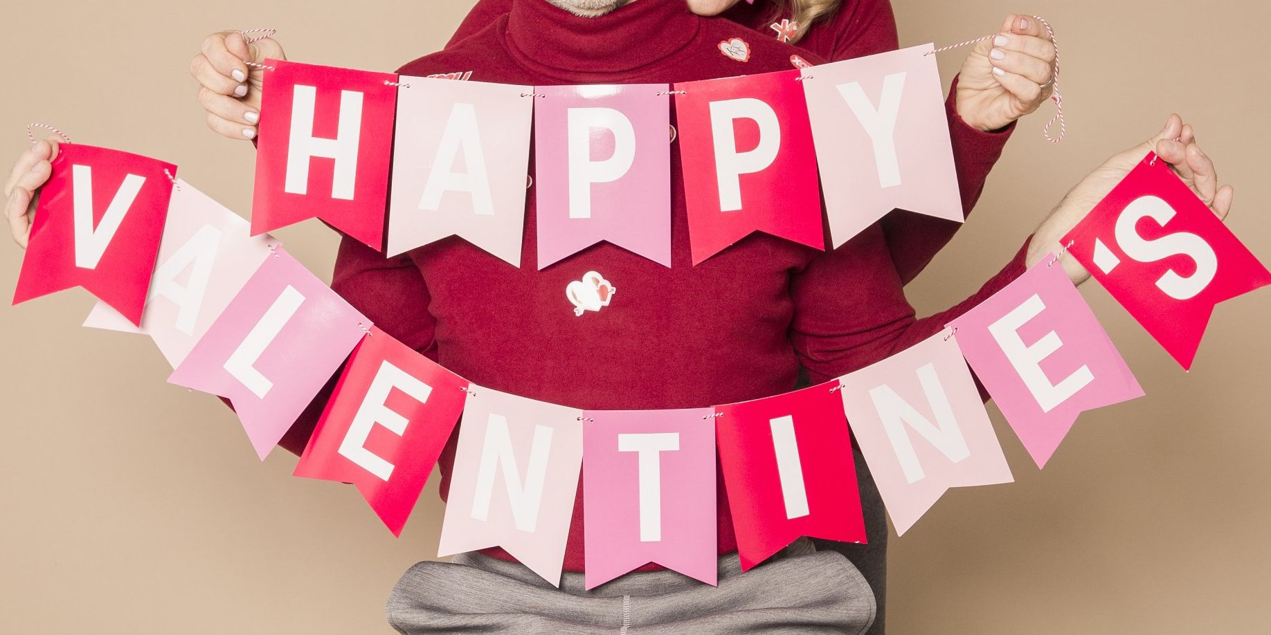 A woman is holding a happy valentine 's day banner.