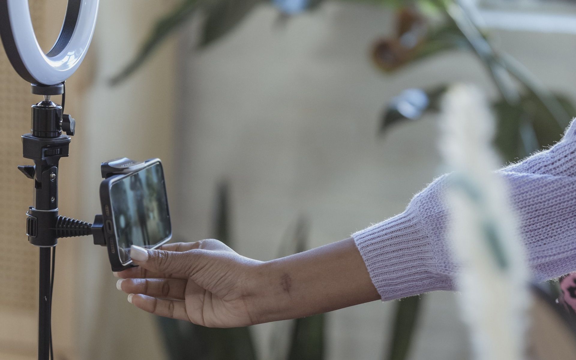 A person is holding a cell phone in front of a ring light.