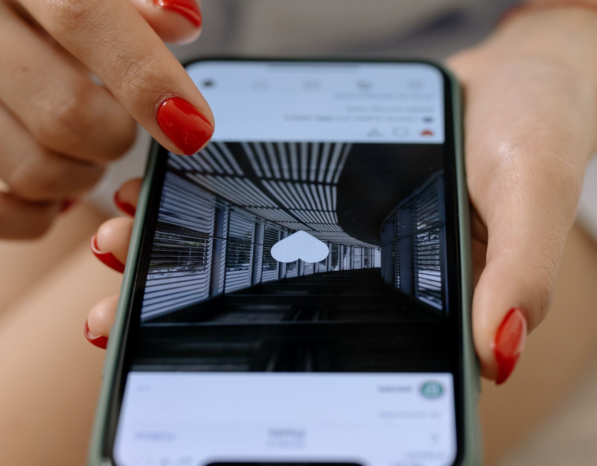 A woman with red nails is holding a cell phone in her hands.