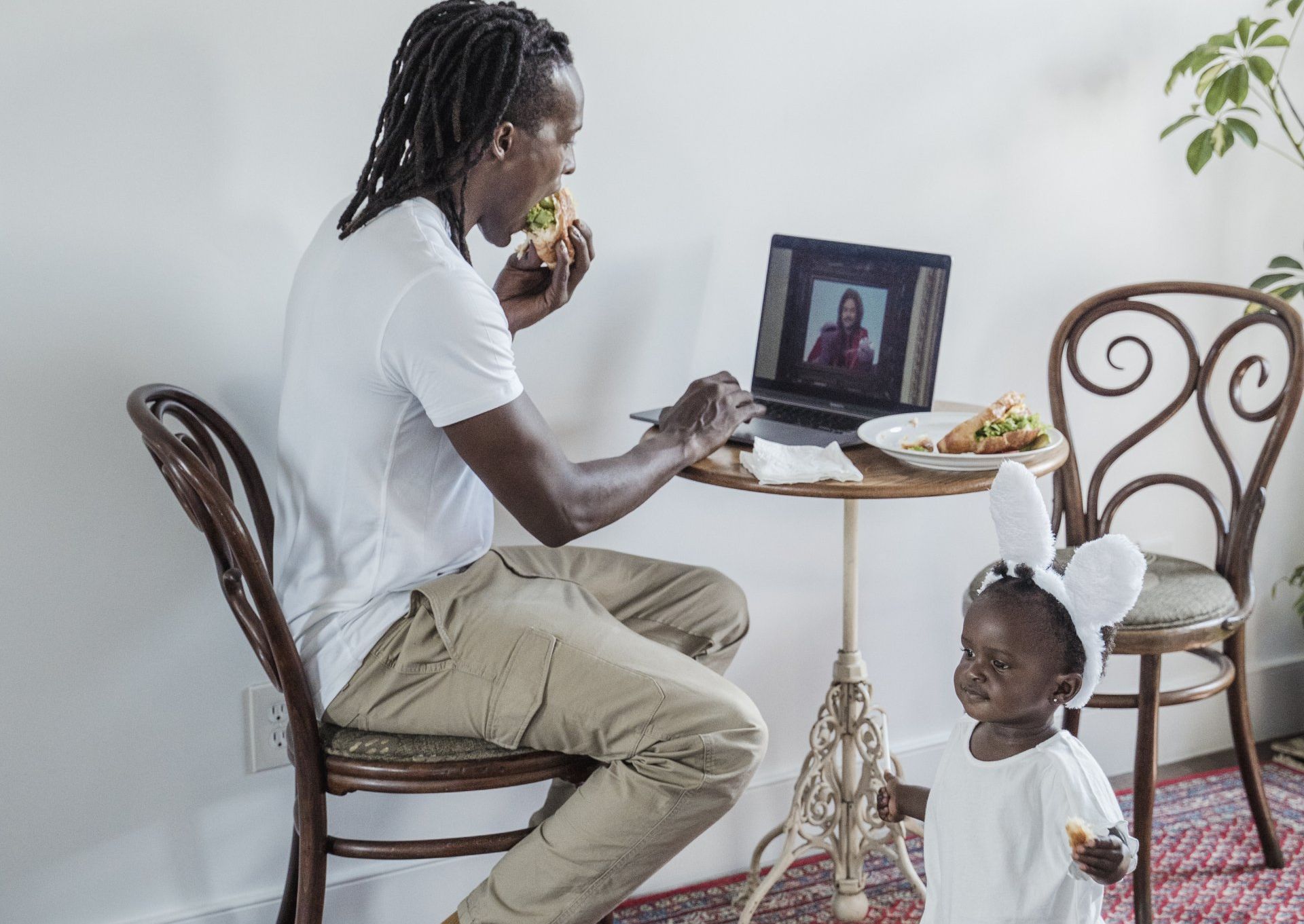 A man and a little girl are sitting at a table with a laptop.