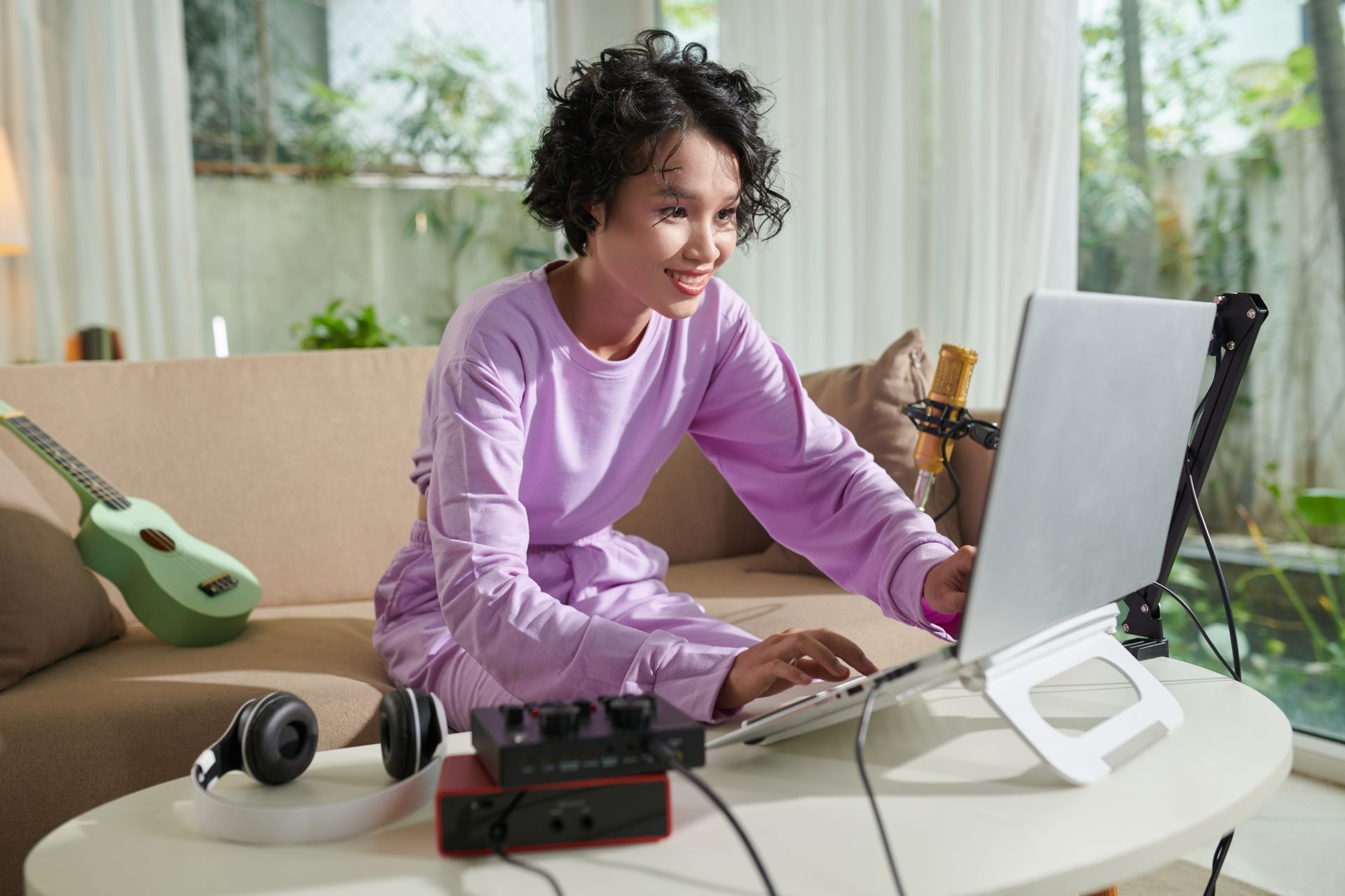A woman is sitting on a couch using a laptop computer.