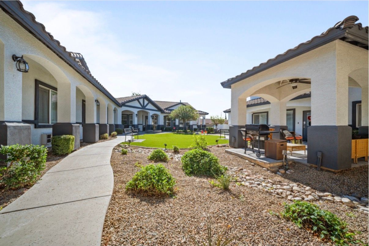 Courtyard walkway between beige apartment buildings with desert landscaping and covered patio seating