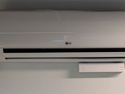 Wall-mounted white LG air conditioner above a small white shelf.