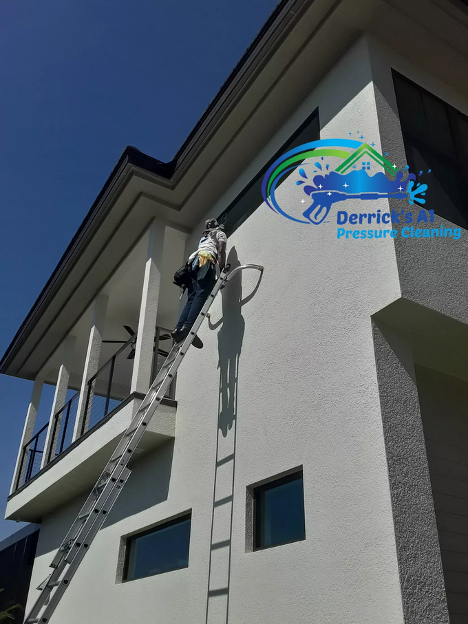 Do you need to clean your exterior surfaces, windows, gutters, or roof? A man on a ladder paints the side of a building