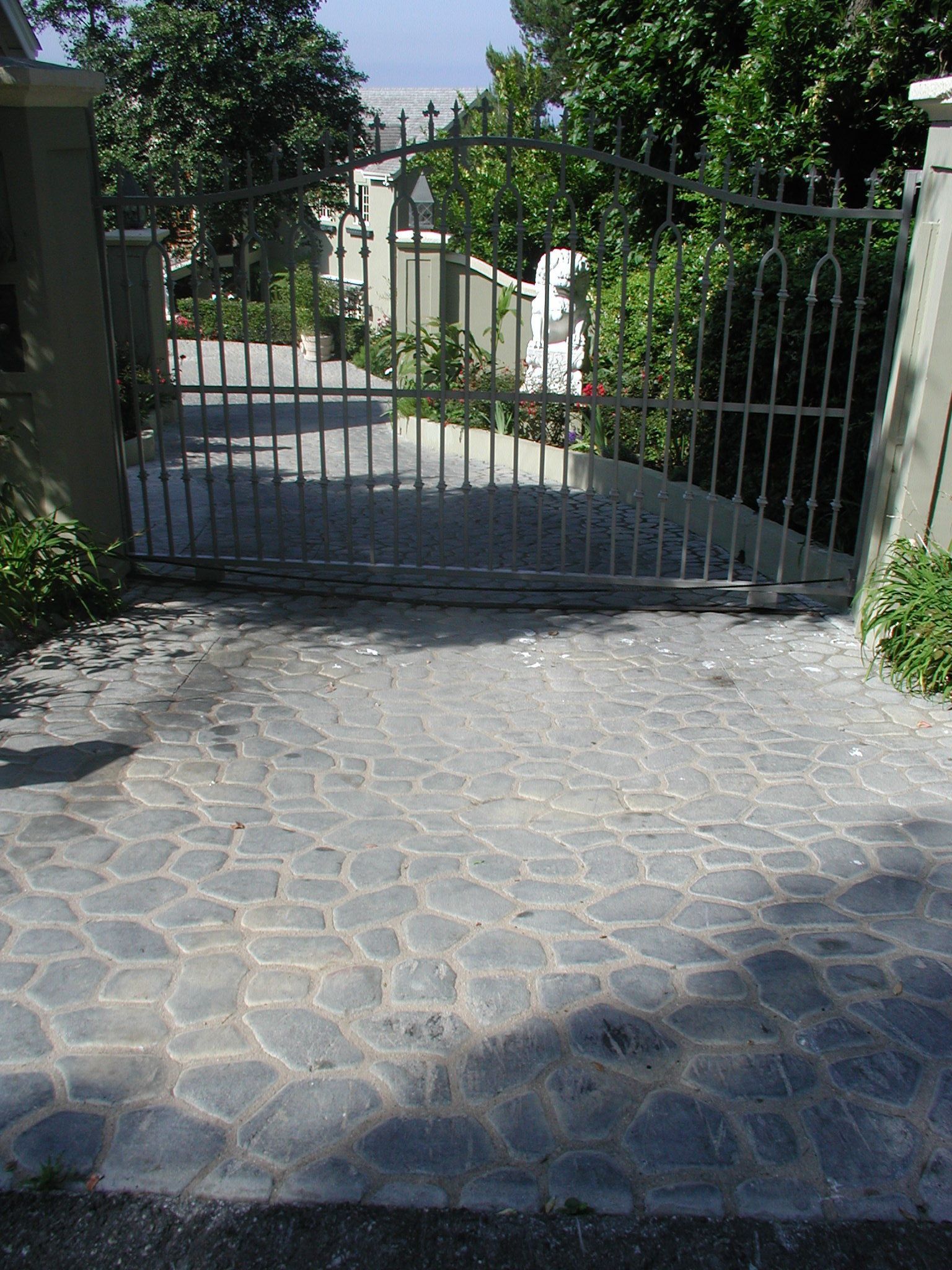 A stone driveway with a metal gate leading to a house
