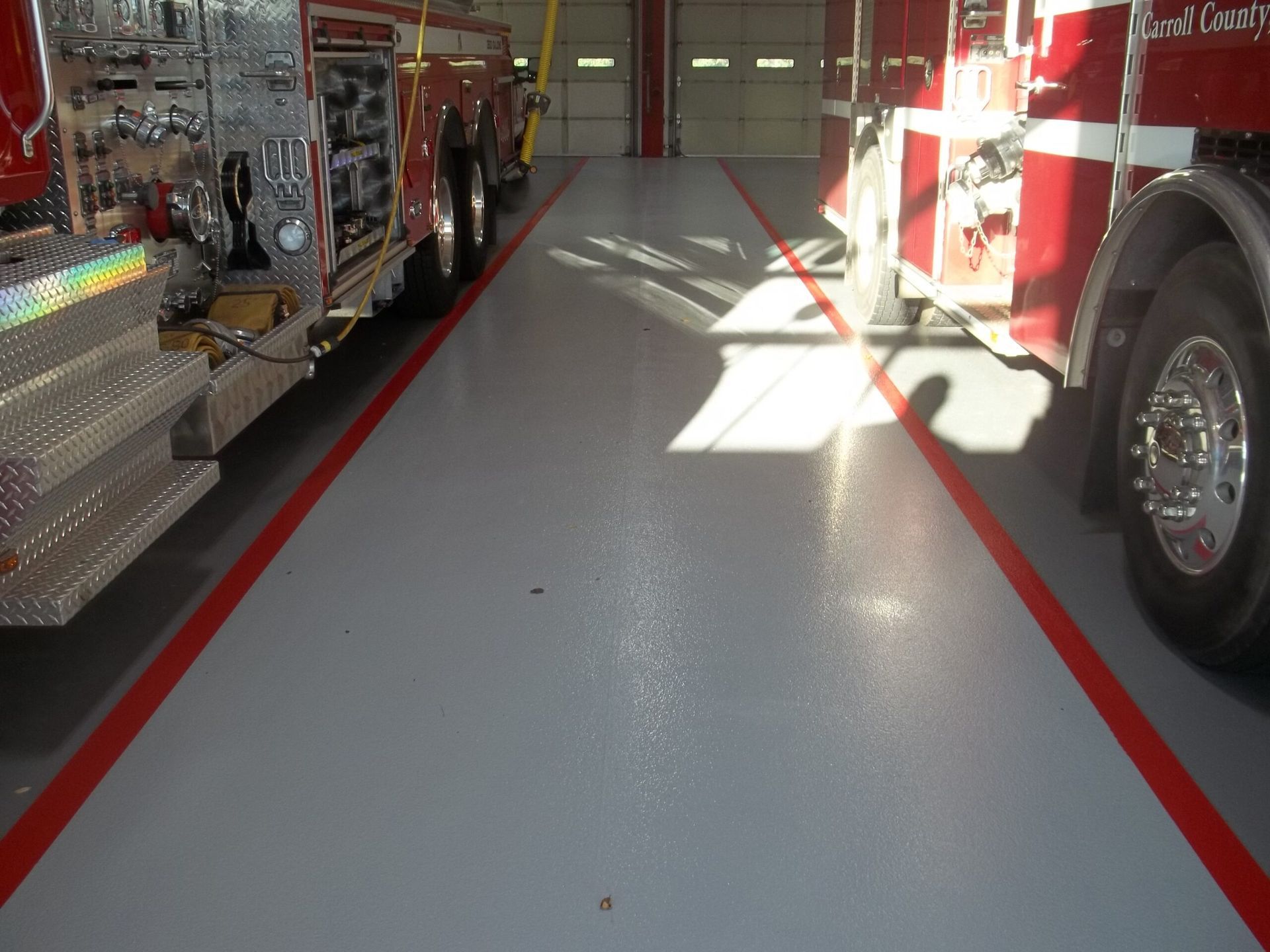 Waypoint Concrete completed epoxy floor coating in a fire station truck bay with red safety striping in Star, Idaho.