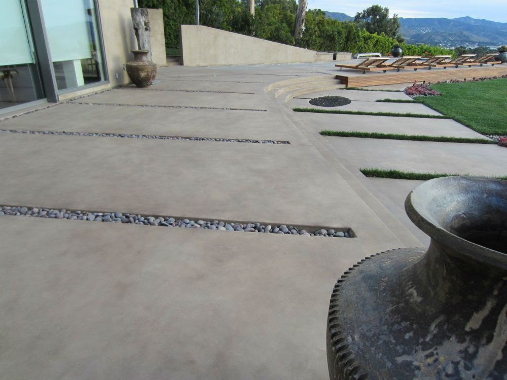 Modern concrete patio with clean lines and decorative rock inlays overlooking a scenic landscape.