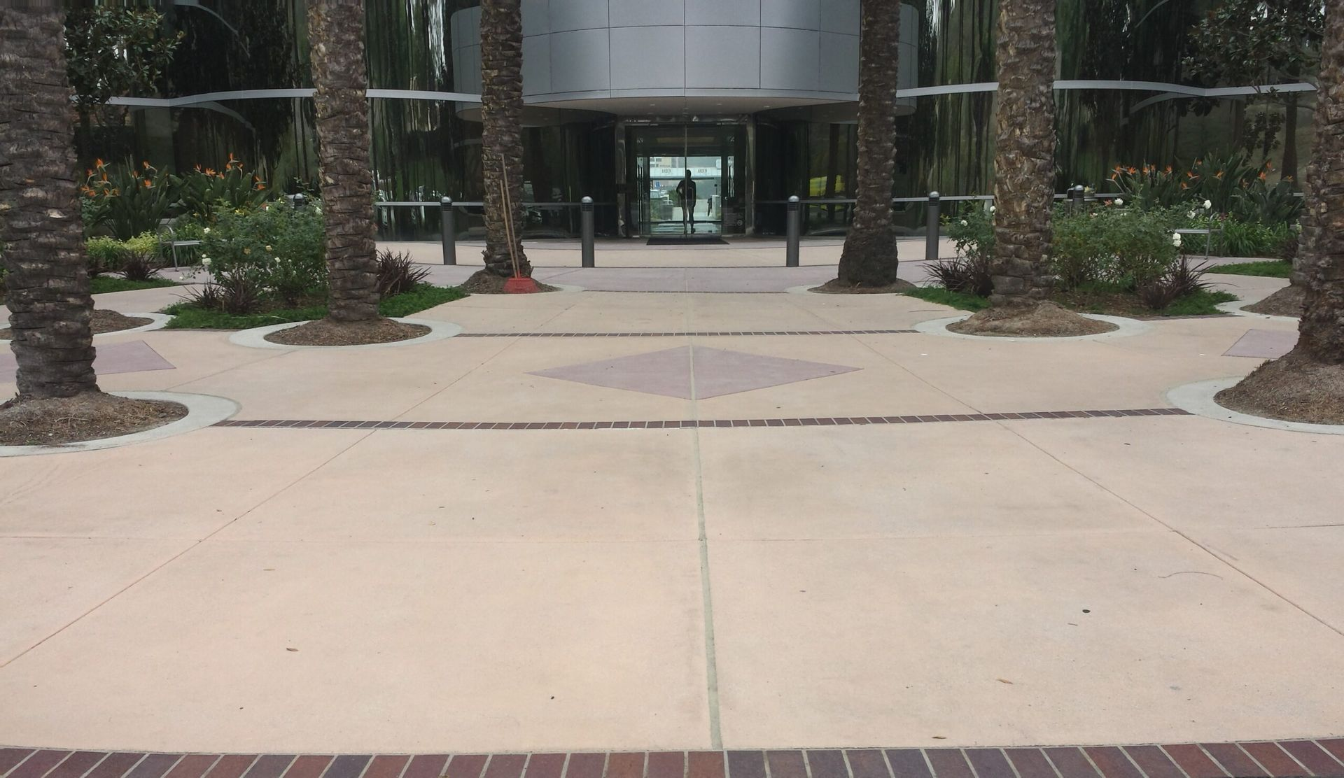 Workers applying concrete stamping mats on wet concrete surface to create decorative patterns during paving process.