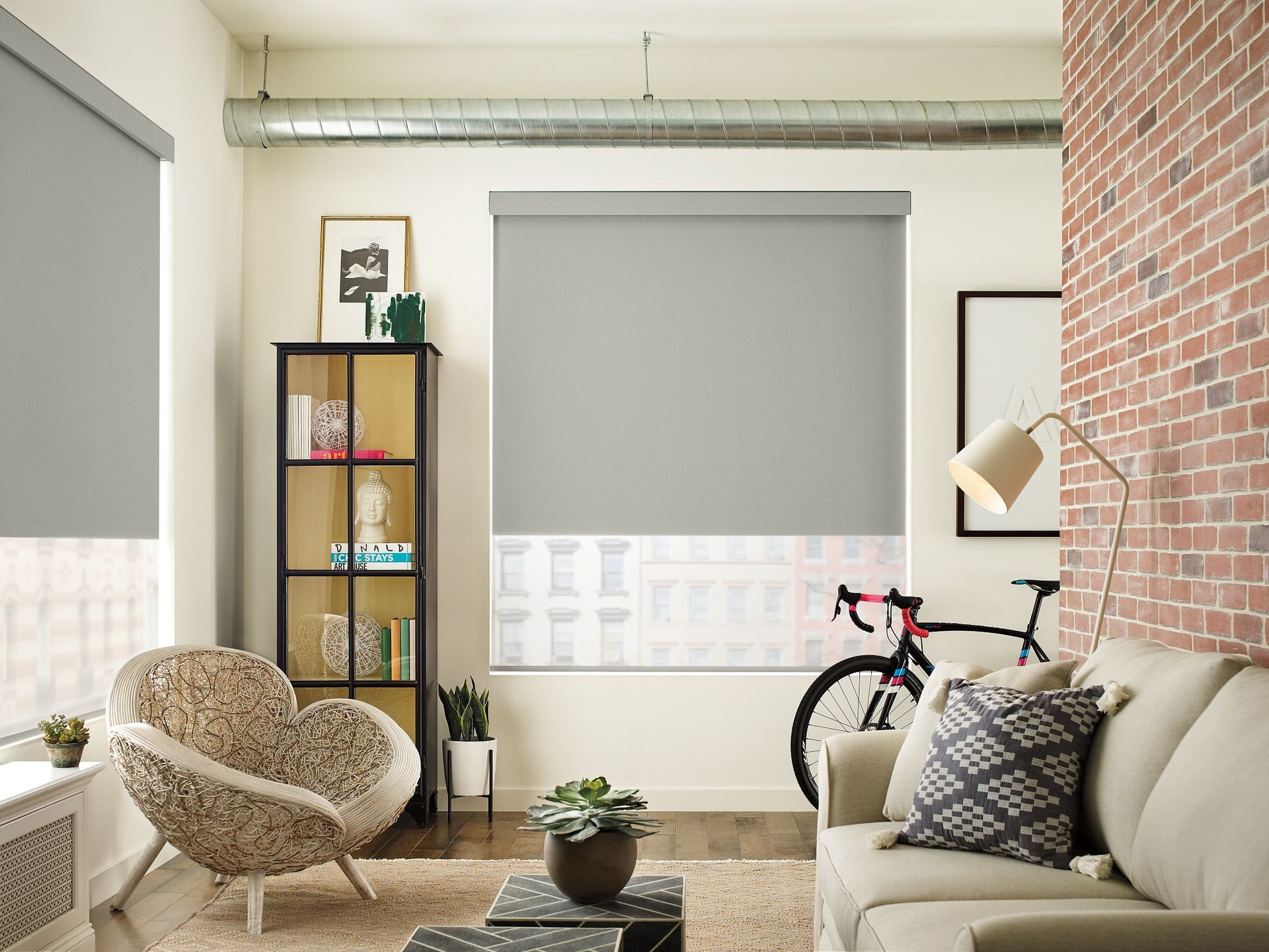Living room with gray roller shades, brick wall, and a bicycle.