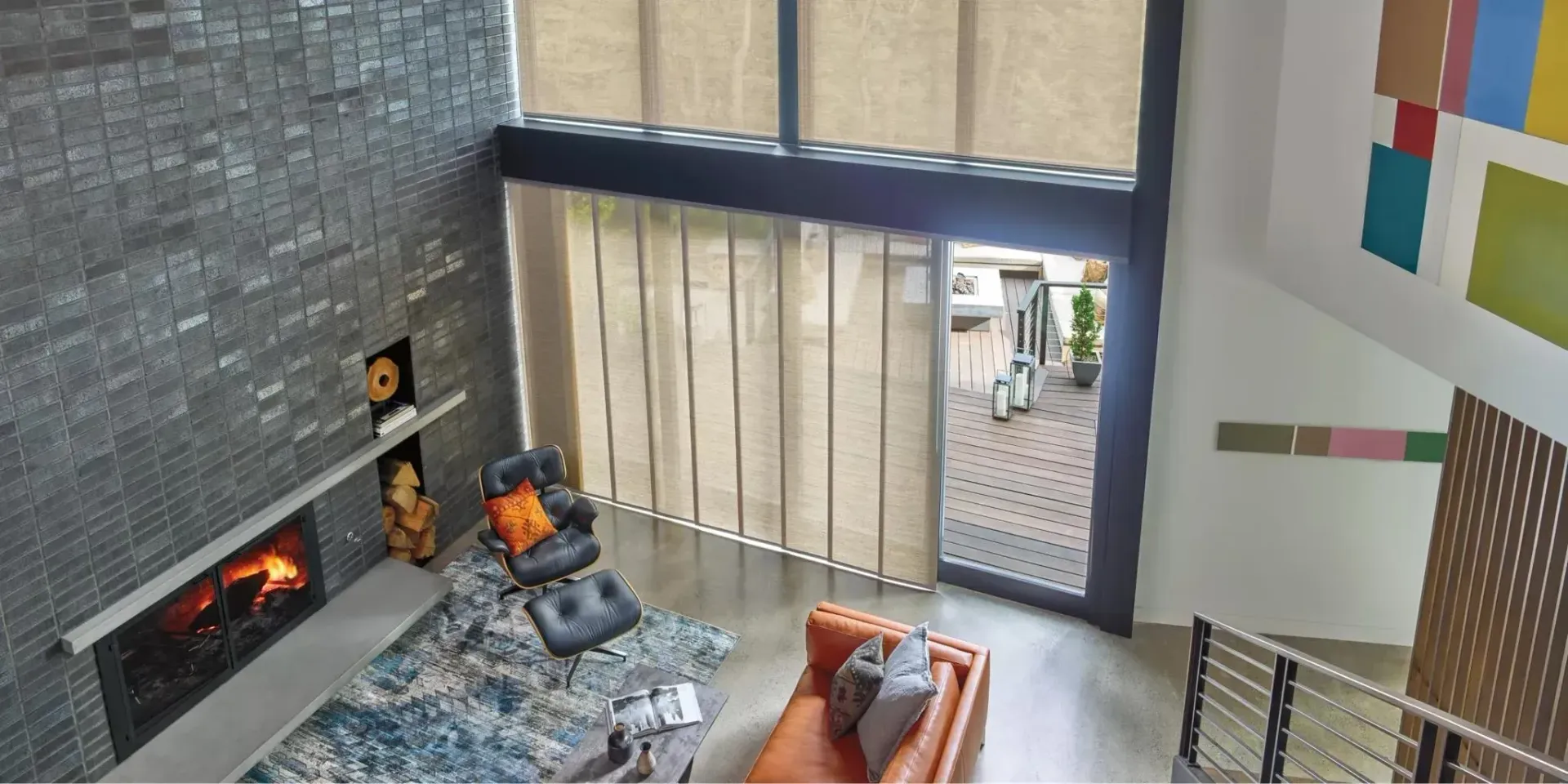Modern living room with fireplace, abstract art, and large windows with blinds.