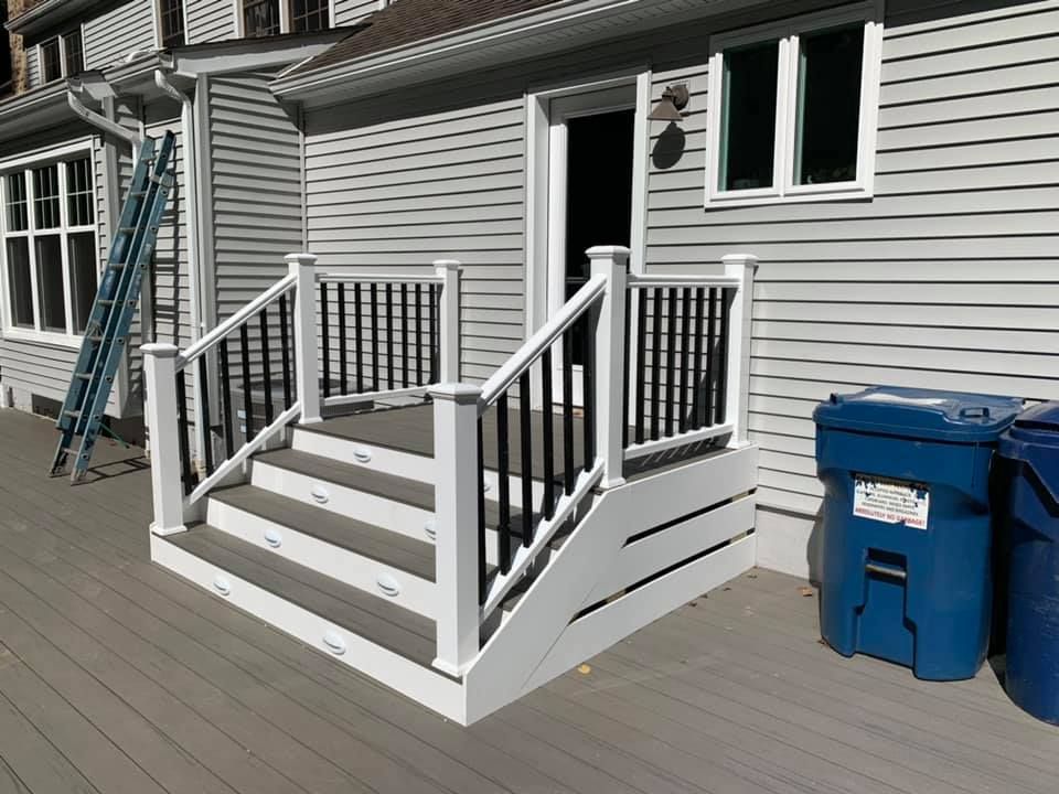 A deck with stairs and a ladder in front of a house.