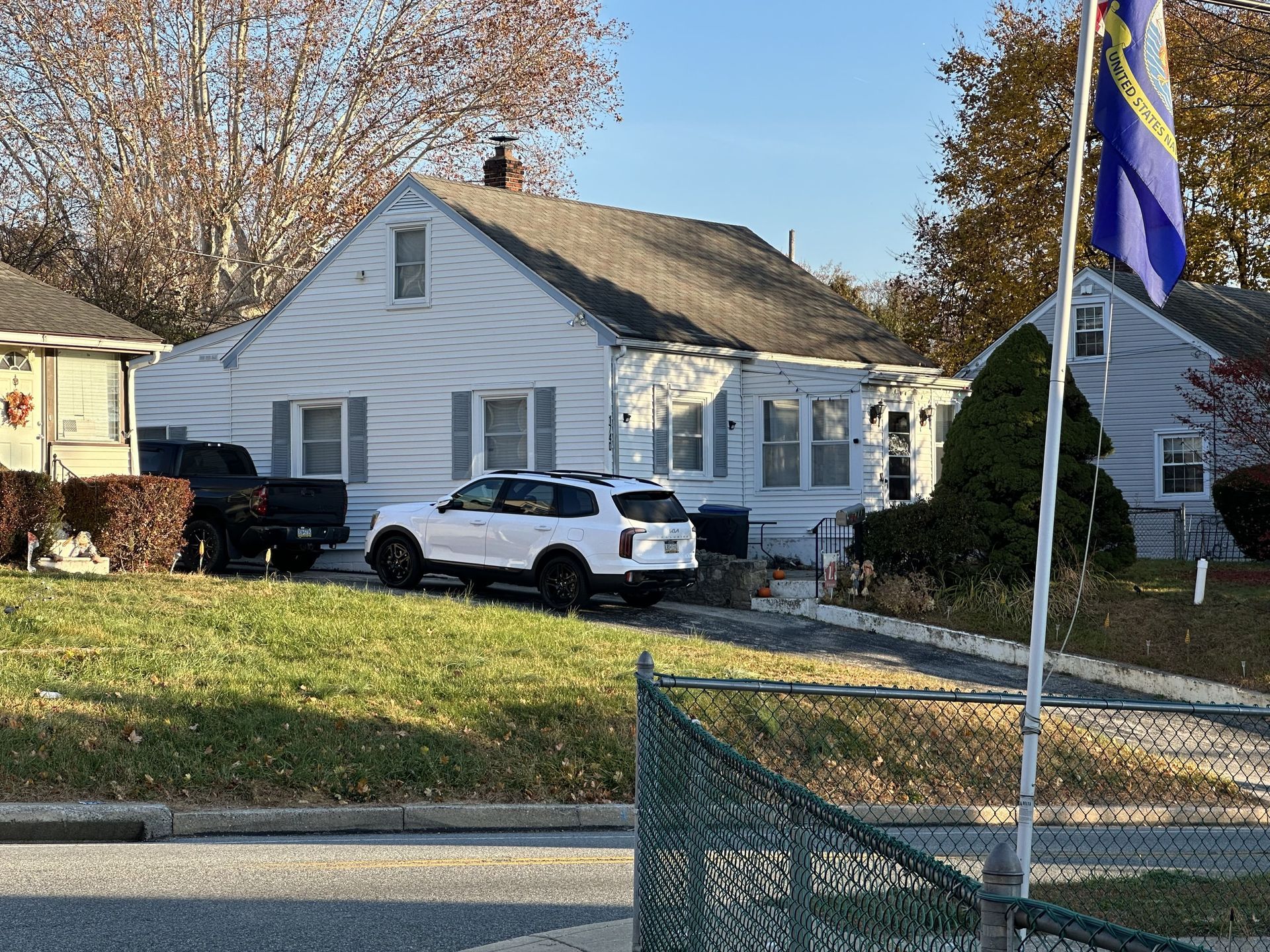 A white suv is parked in front of a white house.