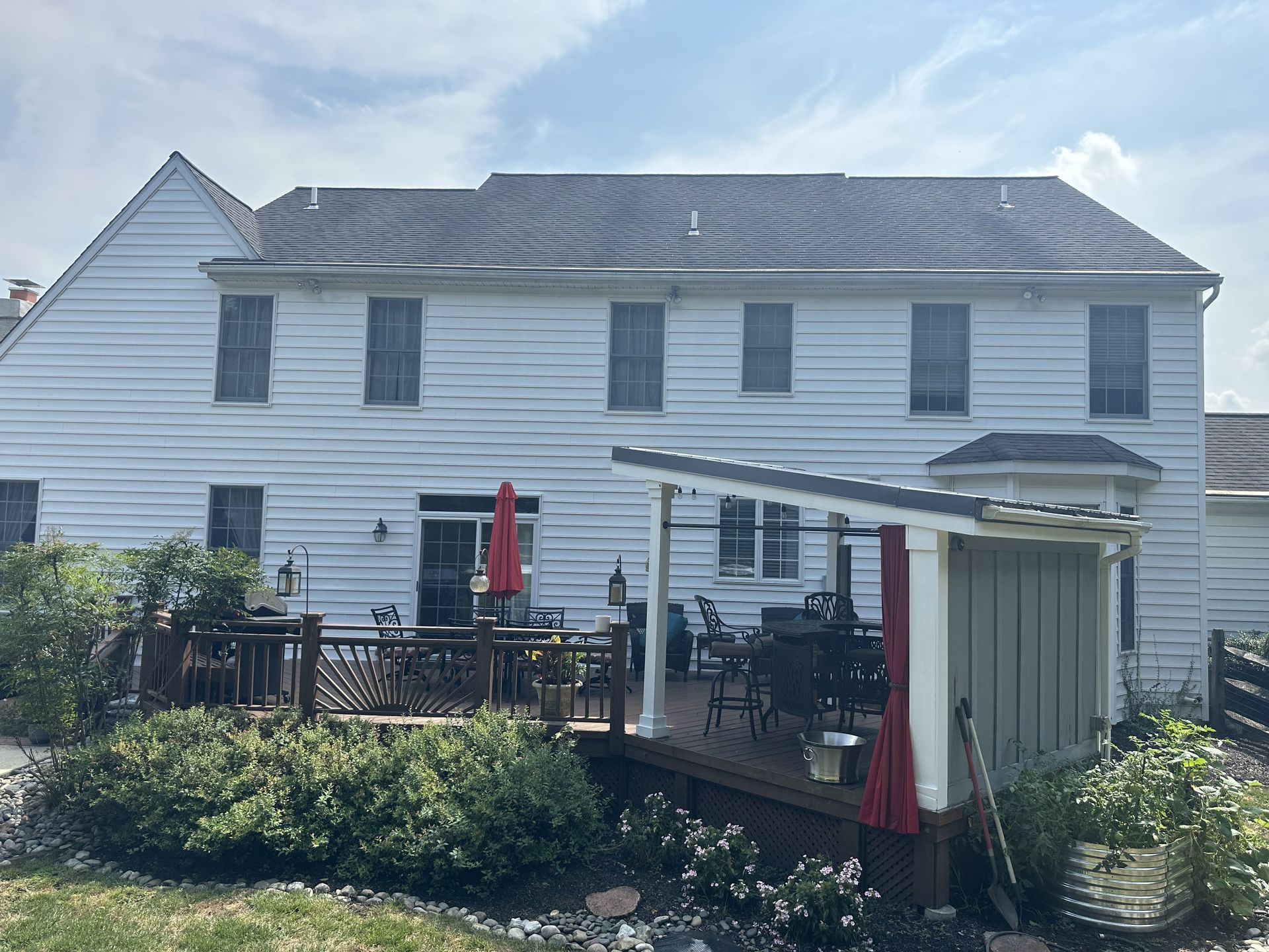 The back of a white house with a deck and umbrellas.