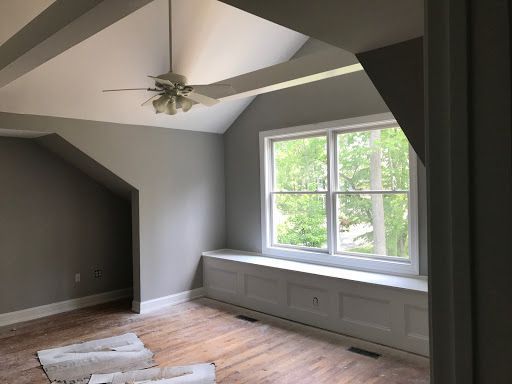 An empty room with a window and a ceiling fan.