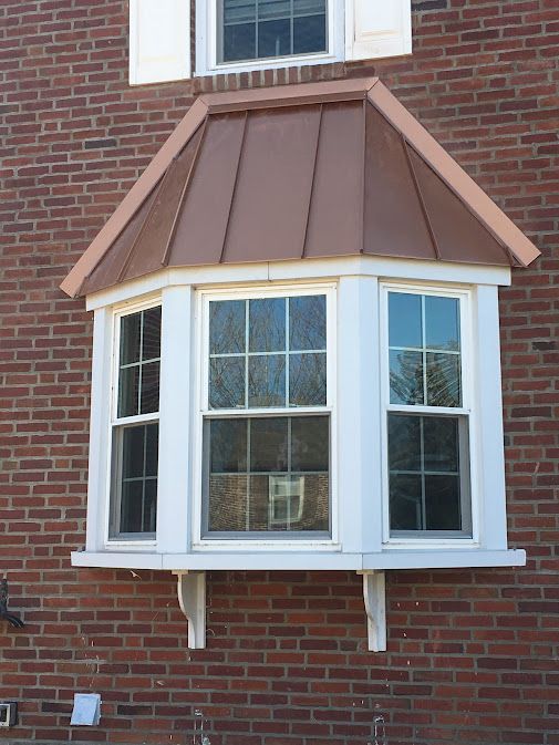 A bay window with a copper roof on a brick building