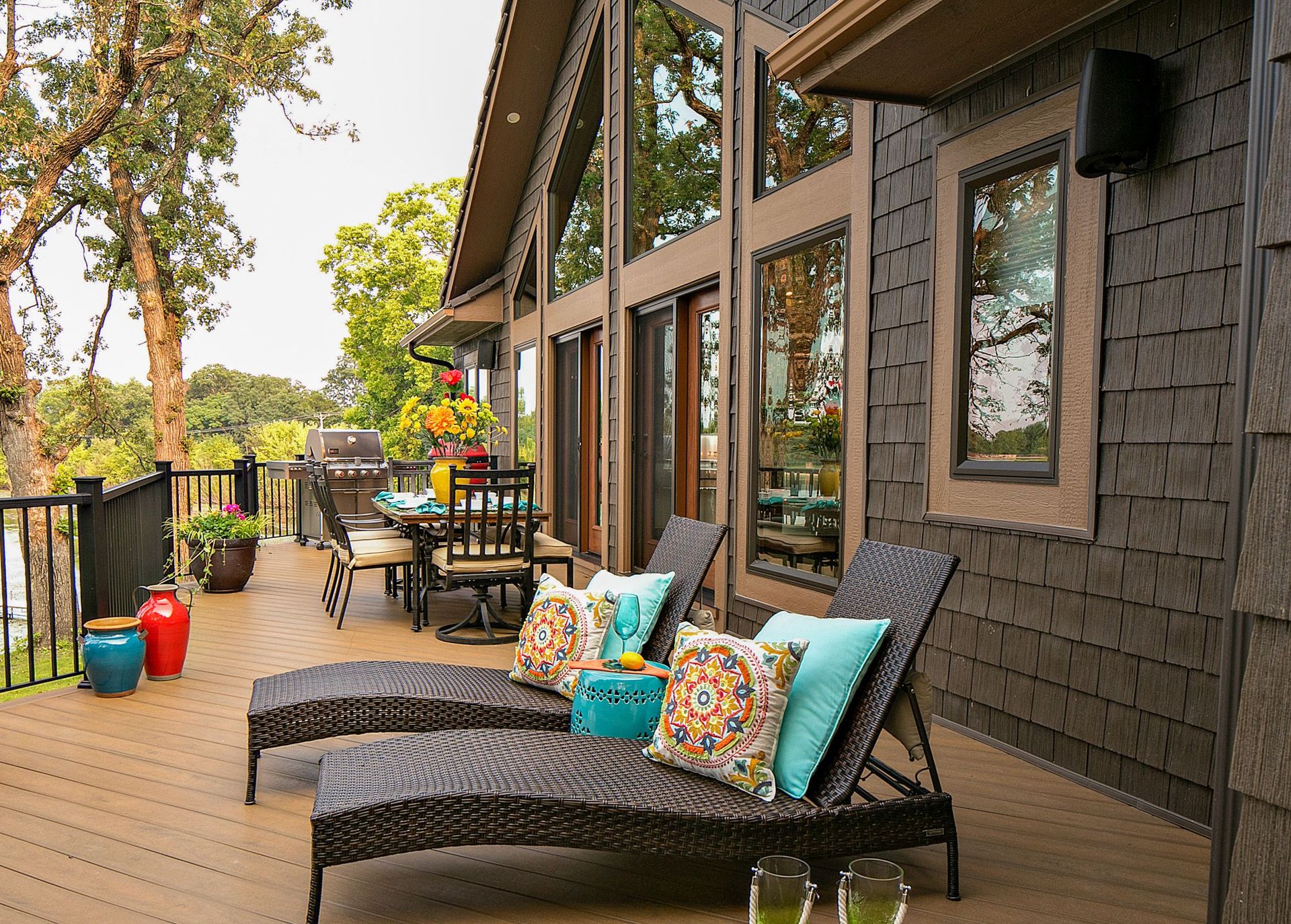 A deck with lounge chairs and a dining table in front of a house.