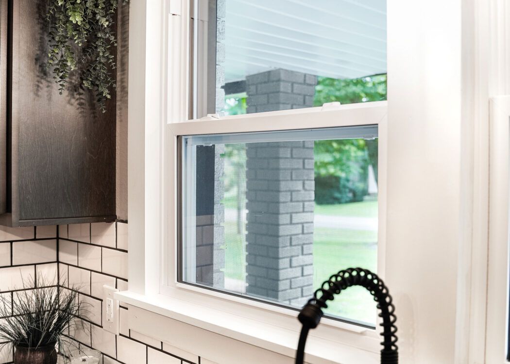 A kitchen with a sink and a window with a view of a brick building.