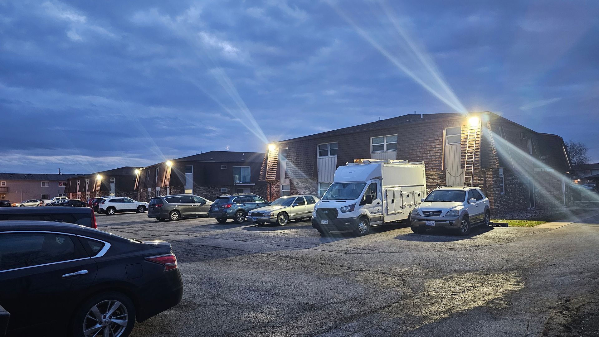 A lot of cars are parked in front of a building at night.