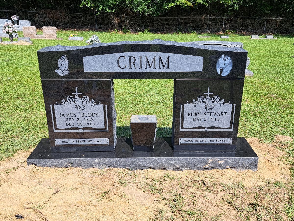 A black granite double headstone for the Crimm family in a cemetery, with etched nameplates and a central vase.