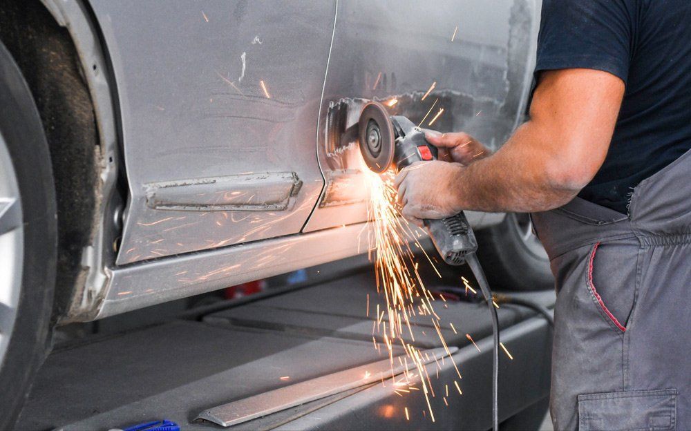 Person Using an Angle Grinder to Repair a Car's Damaged Body Panel — Mid City Smash Repairs in Dubbo, NSW