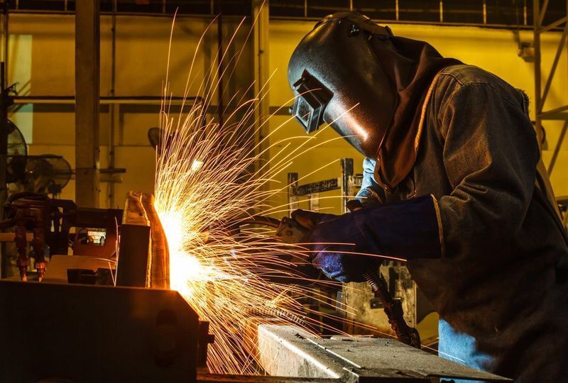 A Welder in Protective Gear Sparks Metal in an Industrial Setting — Mid City Smash Repairs in Dubbo, NSW