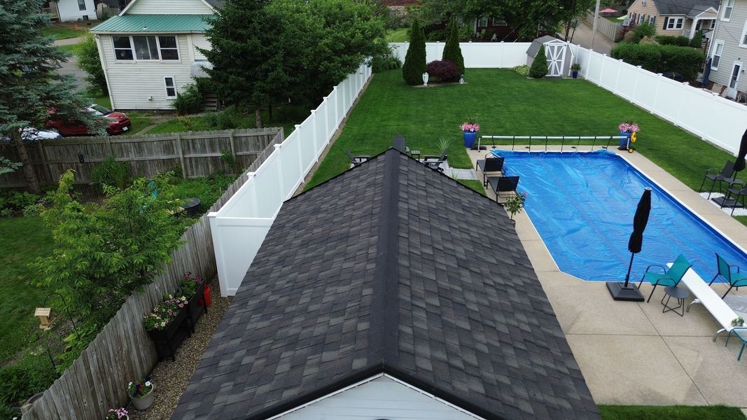 A backyard with a pool, a shed, green grass, and a white fence.