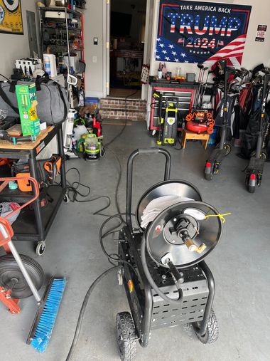Cluttered garage with electric bikes, tools, and a Trump 2024 flag on the back wall.