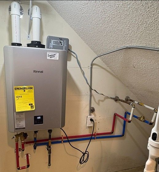 Rinnai water heater with red and blue pipes mounted on a wall in a utility room
