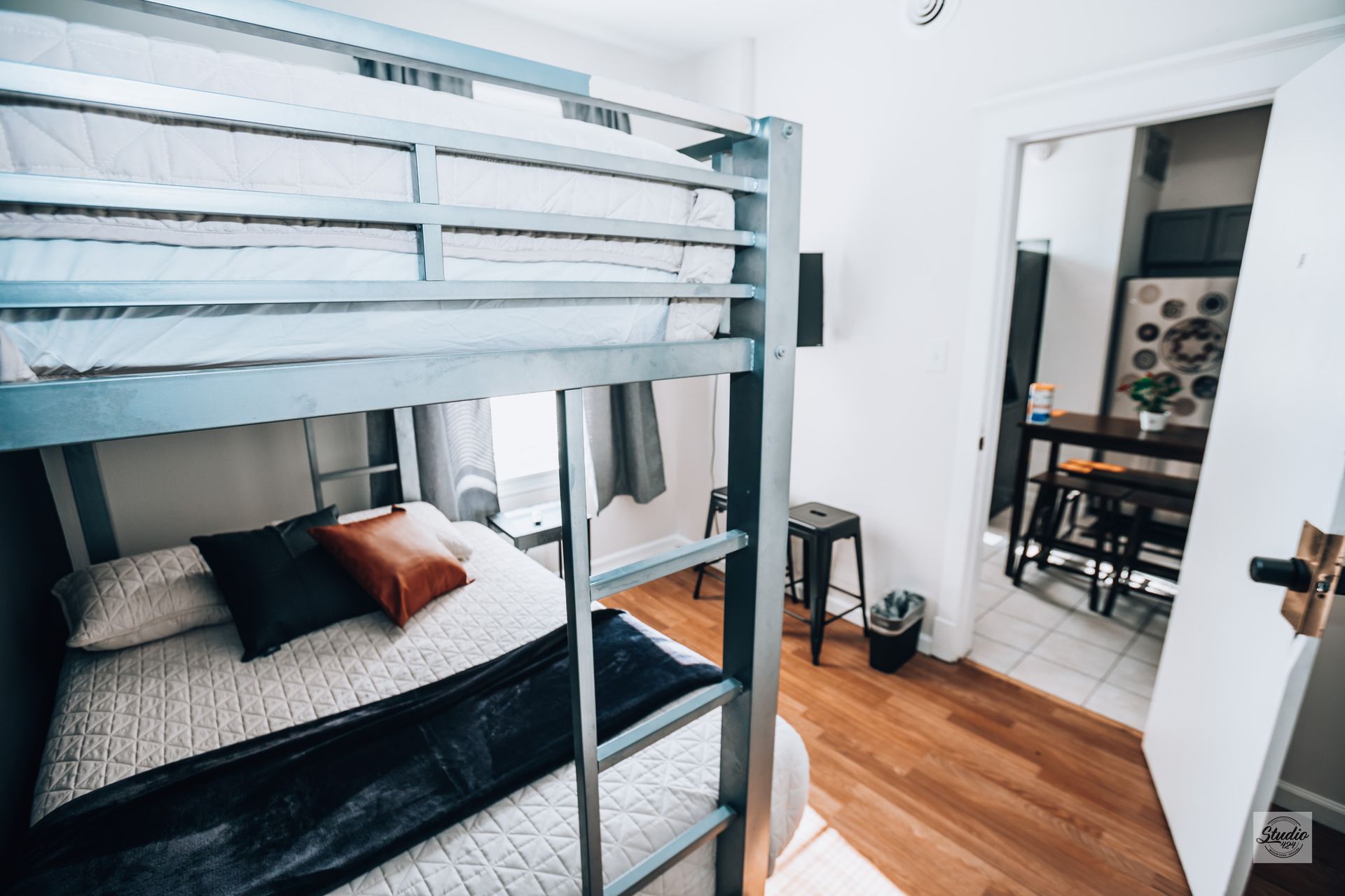 Bunk beds in a bright room with an open doorway to a dining area.