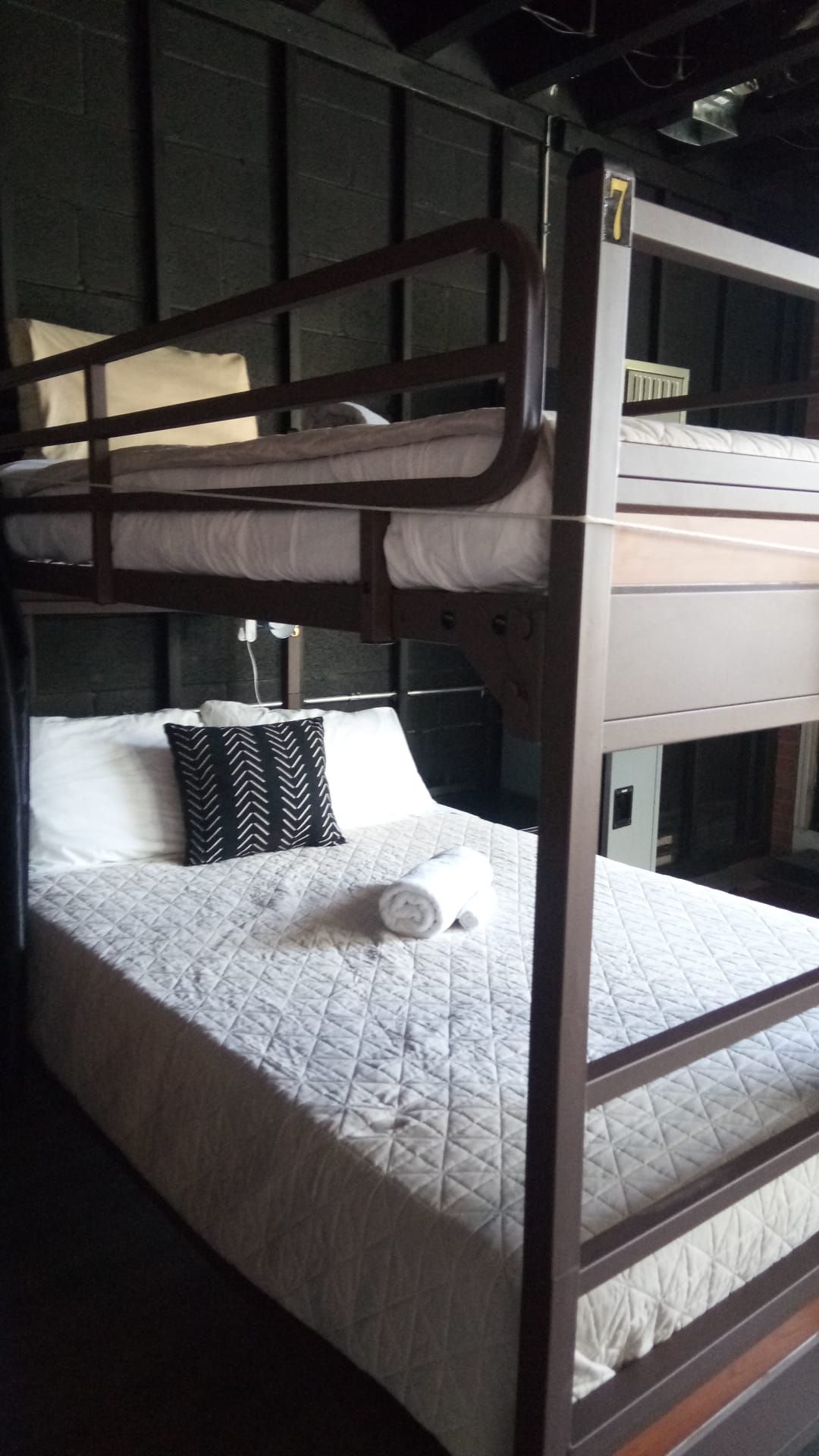 Brown metal bunk beds with white bedding, pillows, and a decorative black and white pillow.
