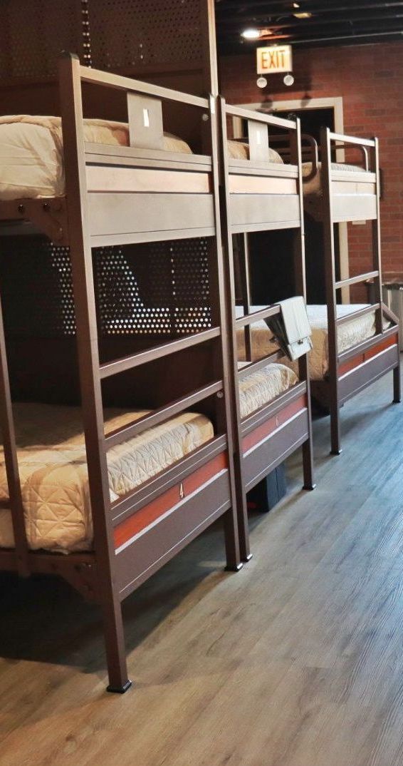 Three wooden bunk beds in a room, with brown frames and mattresses. An