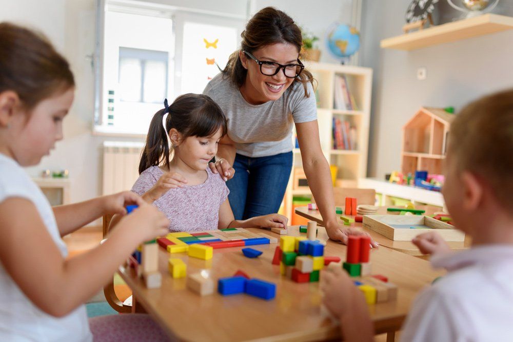 Preschool Teacher With Children Playing With Colourful Wooden Didactic Toys — Grandma Rosie’s Quality Long Day Care In Wollongong, NSW