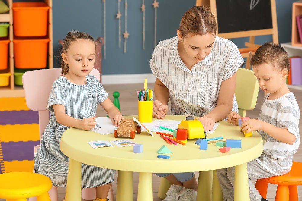 Cute Little Children Playing And Drawing With Teacher — Grandma Rosie’s Quality Long Day Care In Wollongong, NSW