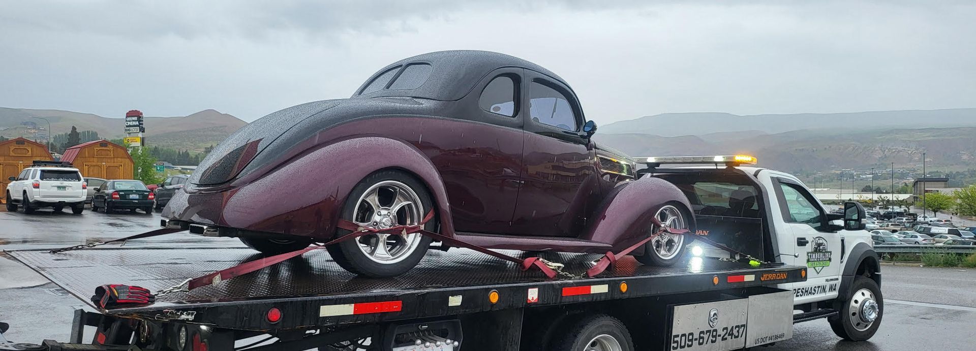 A purple car is being towed by a tow truck.
