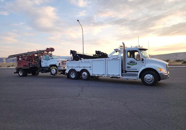 Tow truck hauling another truck on a road at sunset