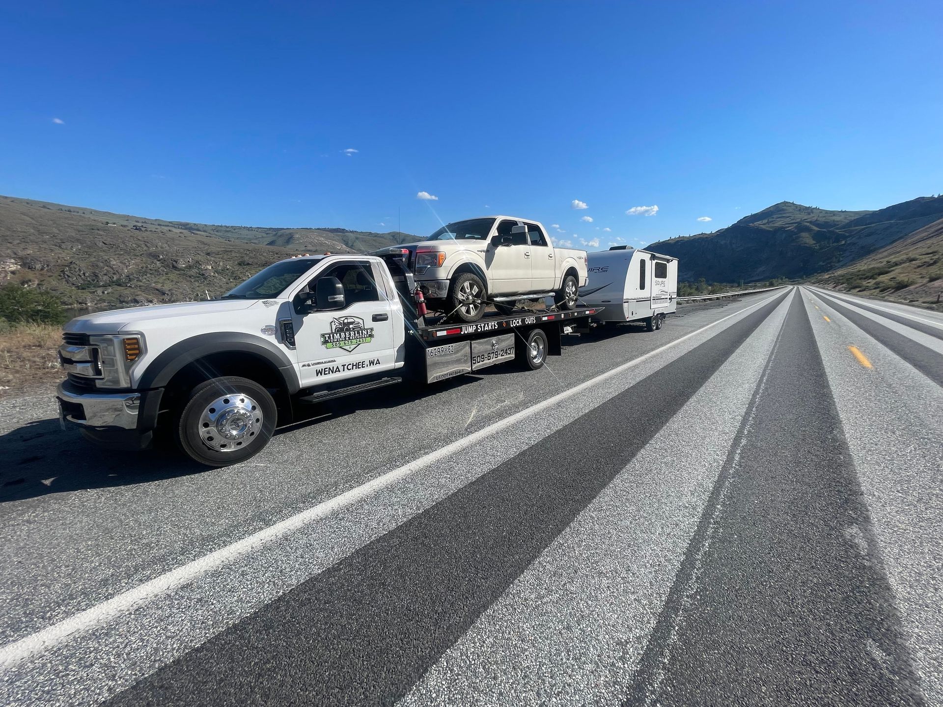 Tow truck hauling vehicles on a desert highway under a clear blue sky