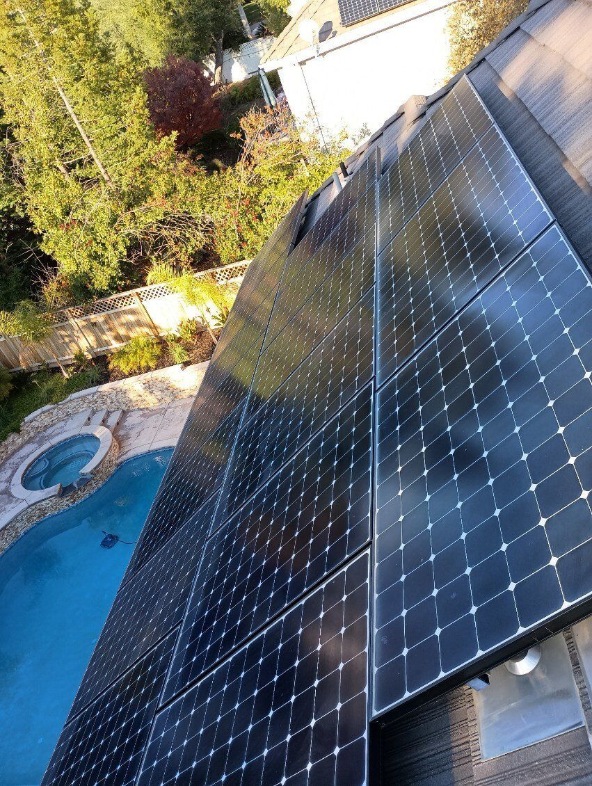 Solar panels on a rooftop, overlooking a pool and trees.
