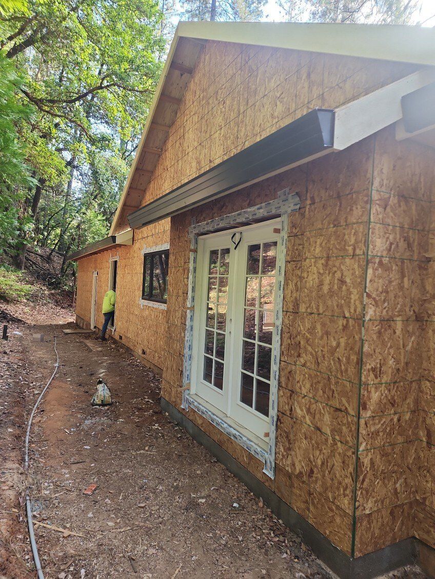 Building exterior under construction, with wood siding, windows, and a gutter.