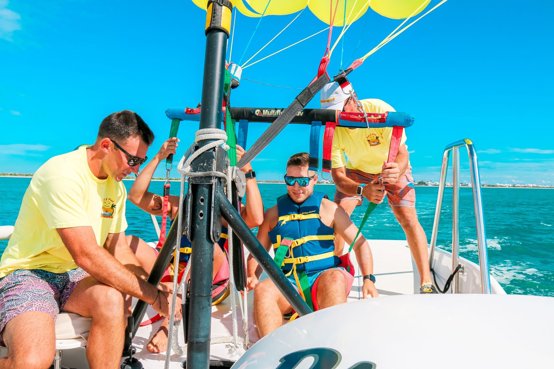 People preparing to parasail from a boat on a sunny day.